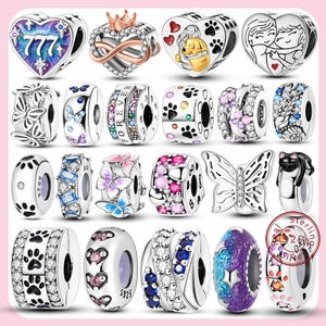 May include: A collection of sterling silver charm beads with various designs. The charms include hearts, butterflies, paw prints, and other decorative elements. Some charms feature colorful accents and sparkling stones.