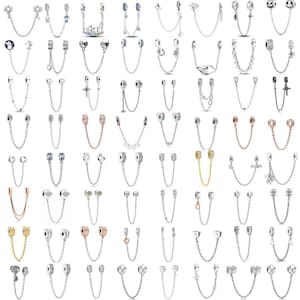 May include: A selection of silver charm bracelet safety chains, each featuring different decorative charms. Charms include hearts, crosses, and stars. The chains are designed to prevent bracelets from being lost.