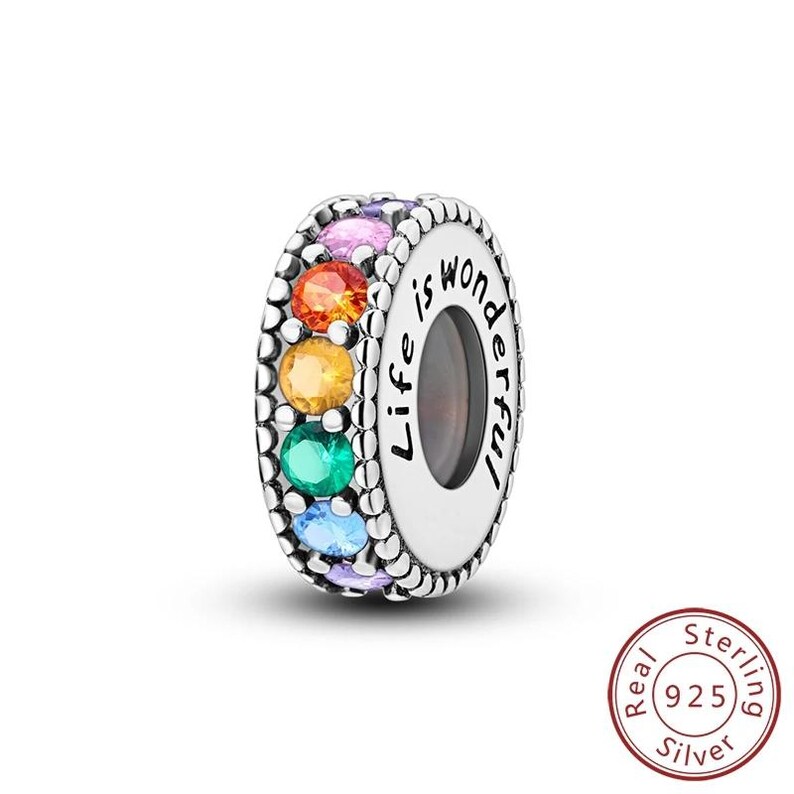 May include: A sterling silver charm with a rainbow of colorful gemstones. The charm is engraved with the words "Life is wonderful". The charm is a bead style and is suitable for bracelets and necklaces.