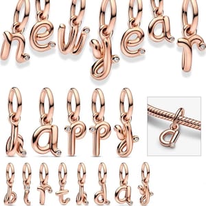 May include: Rose gold-colored alphabet charms with small clear crystals. The charms are in a cursive font and are designed to be added to a bracelet or necklace. The letters include n, e, w, y, a, h, p, p, y, b, i, r, t, h, d, a, y.