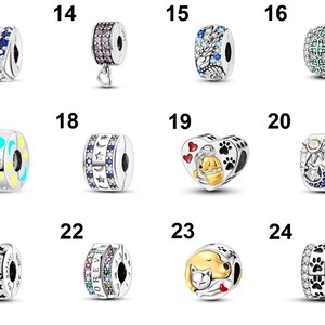 May include: A collection of silver charm beads with various designs. Some beads feature colorful gemstones, while others have celestial motifs like stars and moons. Several charms have heart, paw print, and Winnie the Pooh designs.