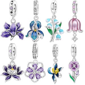 Könnte beinhalten: Eine Sammlung silberner Blumenanhänger mit farbenfrohen Emaille-Details. Die Anhänger zeigen verschiedene Blumendesigns, darunter Iris, Lilien und Stiefmütterchen. Jeder Anhänger hat eine dekorative Öse mit funkelnden Akzenten, ideal für Armbänder oder Halsketten.