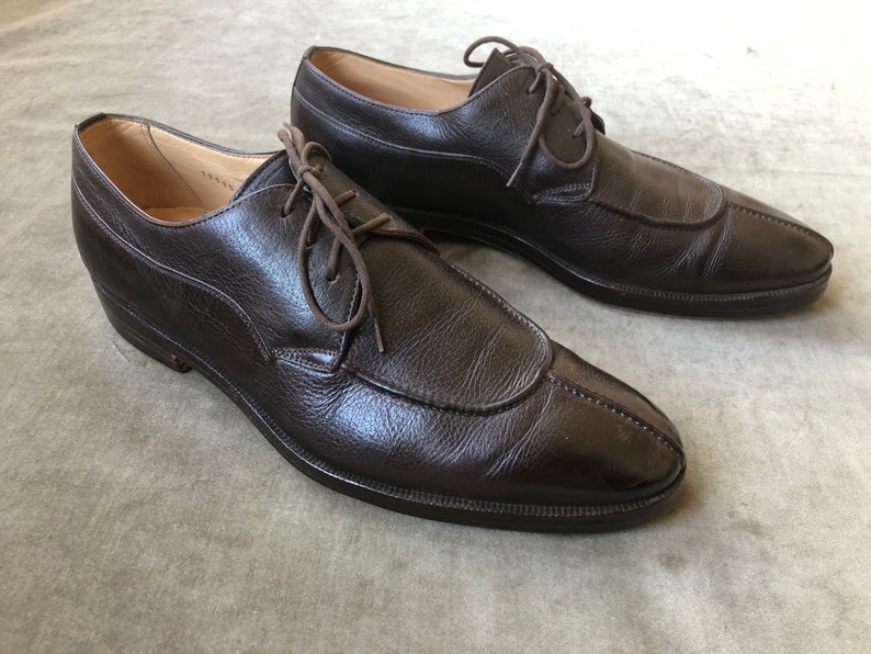 Puede incluir: Un par de zapatos marrones de cuero con cordones y punta puntiaguda.