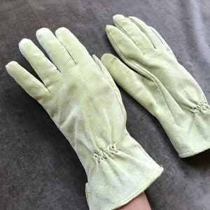 May include: A pair of light green leather gloves with a stitched detail at the wrist.