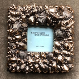 May include: A gold-toned picture frame with a seashell design. The frame is 3 x 3 inches and has a white mat with the text "Mitchell Gold + Bob Williams" and "3 x 3 Inches".