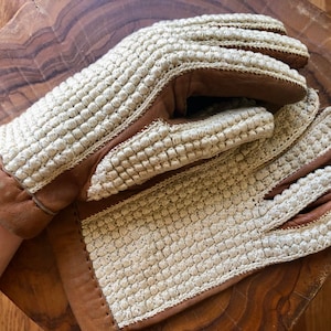 May include: A pair of brown leather gloves with a white crocheted pattern. The gloves are made of a soft, comfortable material and have a classic design.