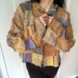 May include: A brown, yellow, and blue patchwork jacket with frayed edges. The jacket has a collar and a button closure.