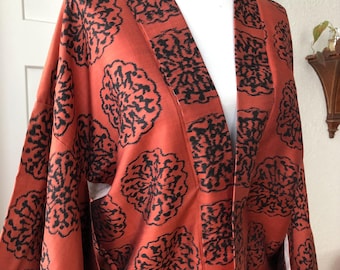 May include: A long, red kimono with a black floral pattern. The kimono is made of a silky fabric and has a traditional Japanese design.