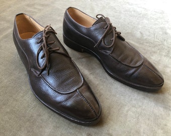 Puede incluir: Un par de zapatos marrones de cuero con cordones y punta puntiaguda.