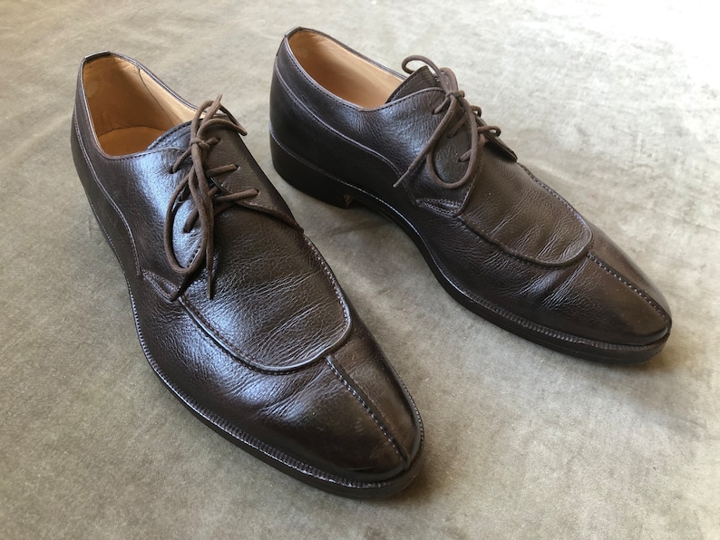 Puede incluir: Un par de zapatos marrones de cuero con cordones y punta puntiaguda.