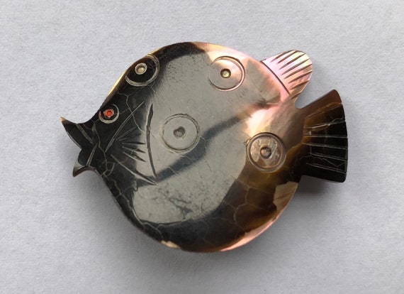 A tiny carved abalone seashell puffer fish brooch — the kind of weird-cute vintage find you'd spot at a beach antique shop and immediately buy for yourself.