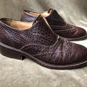 May include: A pair of brown leather shoes with a textured finish. The shoes have a lace-up design and a brogue detail.