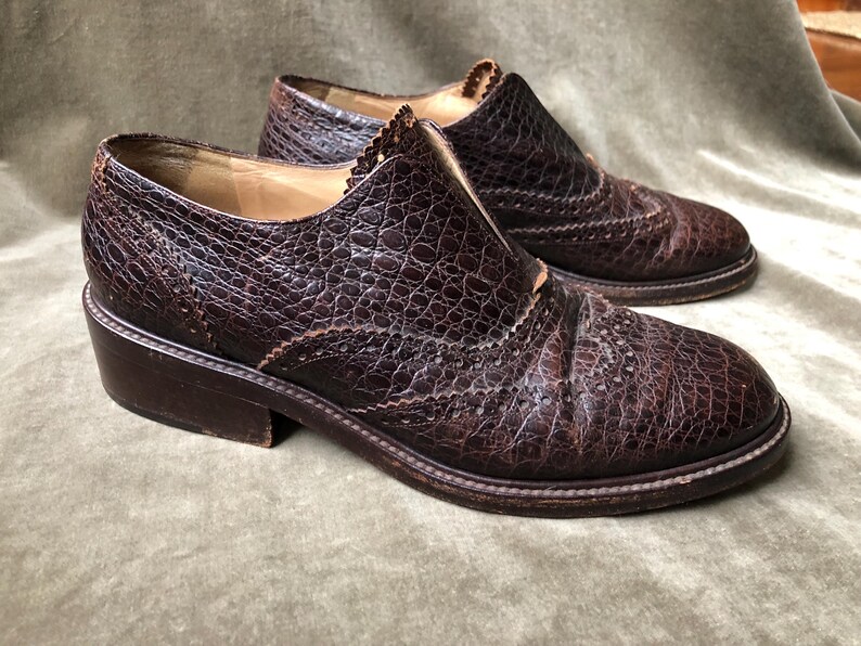 May include: A pair of brown leather shoes with a textured finish. The shoes have a lace-up design and a brogue detail.