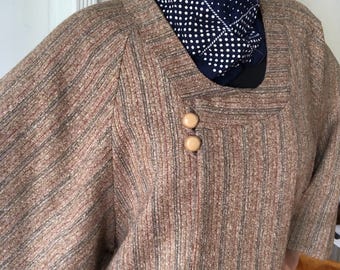May include: A brown and tan striped jacket with a wide collar and large sleeves. The jacket has two large buttons on the front. The person wearing the jacket is also wearing a navy blue bandana with white polka dots.