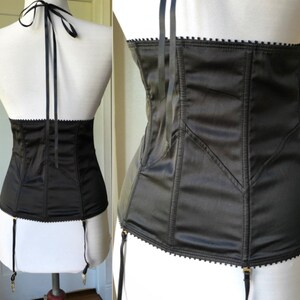 Pode incluir: Corpete de cetim preto com al&ccedil;as ajust&aacute;veis e presilhas para ligas. O corpete tem uma estrutura de varas e uma borda festonada.