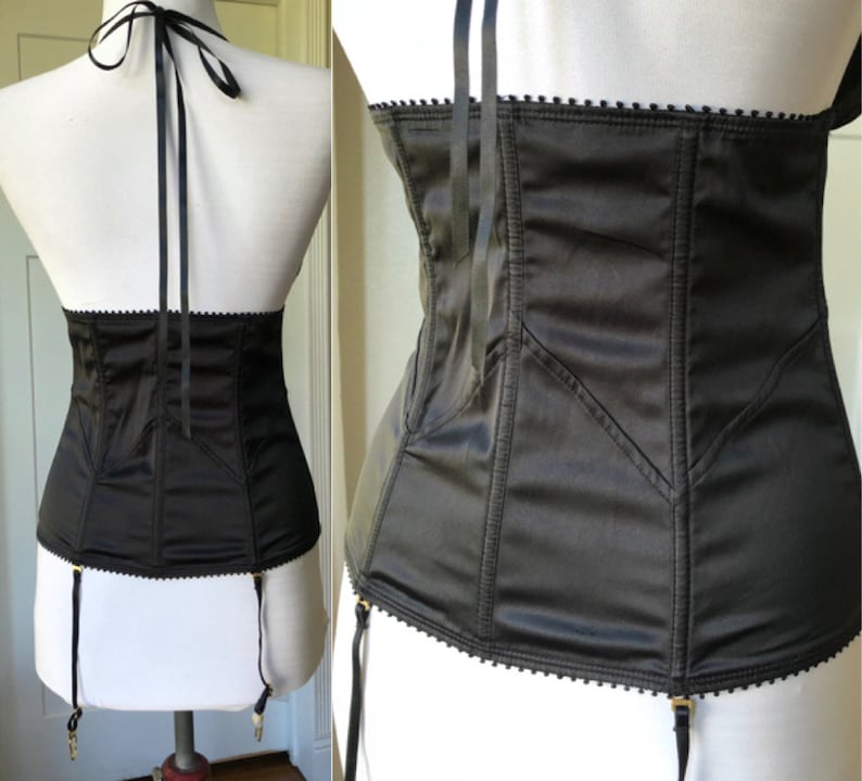 Pode incluir: Corpete de cetim preto com al&ccedil;as ajust&aacute;veis e presilhas para ligas. O corpete tem uma estrutura de varas e uma borda festonada.