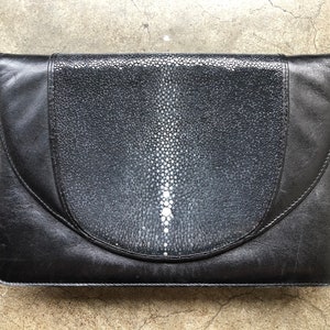 May include: A black leather shoulder bag with a unique, textured, white and black pattern on the front flap.