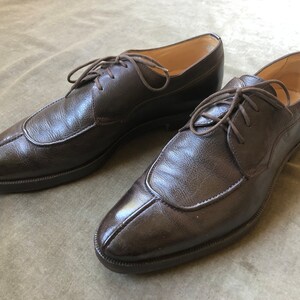 Puede incluir: Un par de zapatos marrones de cuero con cordones y punta puntiaguda.