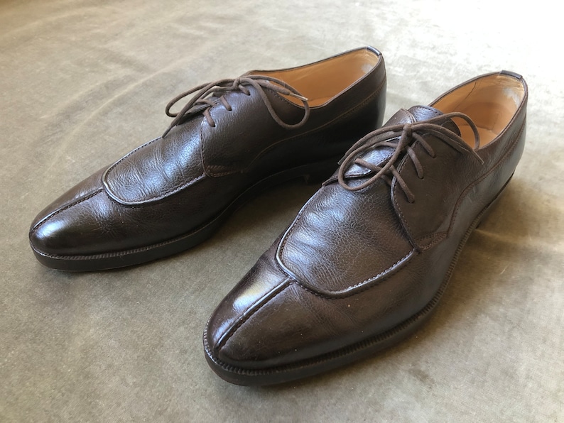 Puede incluir: Un par de zapatos marrones de cuero con cordones y punta puntiaguda.