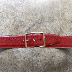 May include: A red leather belt with a gold metal buckle.