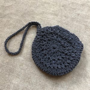 May include: A black crocheted purse with a round shape and a long strap.
