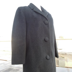 May include: A long-sleeved, dark gray wool coat with a classic collar and three black buttons down the front.