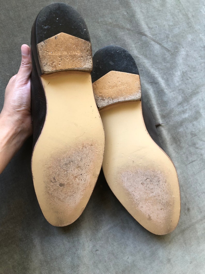 Puede incluir: Primer plano de las suelas de dos zapatos de cuero marr&oacute;n. Las suelas est&aacute;n hechas de cuero marr&oacute;n claro y tienen un patr&oacute;n texturizado. Los zapatos est&aacute;n hechos en Italia.