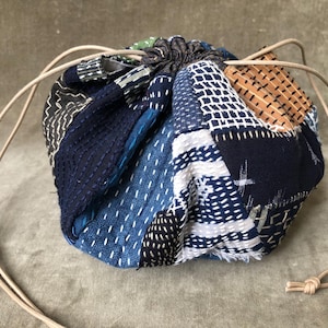 Bolso kimono redondo con cordón ajustable, estilo dumpling, hecho a mano, con costura sashiko japonesa vintage, patchwork, color índigo, blanco, marrón claro y azul textil.