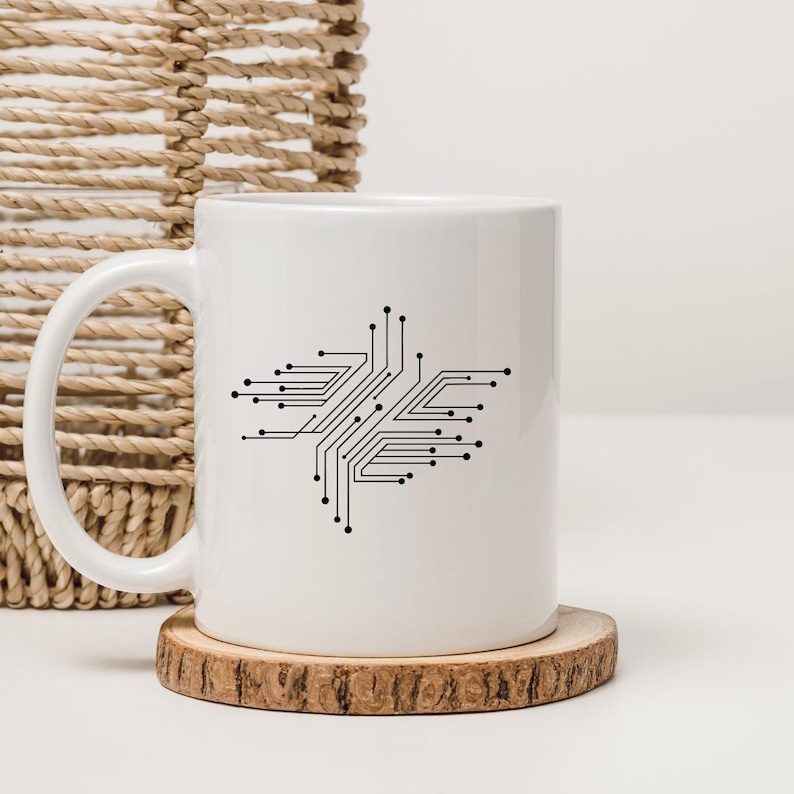 May include: White ceramic coffee mug featuring a black circuit board design. The mug sits on a round wooden coaster. A woven basket is visible in the background.