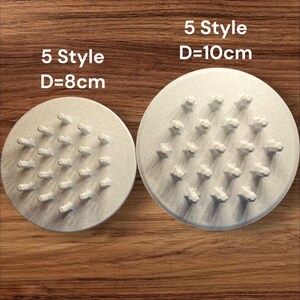 May include: Two beige circular objects with raised, star-shaped protrusions. The smaller one is 8 cm in diameter, and the larger one is 10 cm in diameter. The text "5 Style" is printed on both. The objects are on a wooden surface.