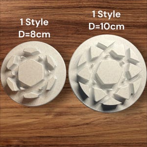 May include: Two off-white, circular molds with geometric designs. The molds are labelled "1 Style" and have diameters of 8cm and 10cm. The molds are on a wooden surface. The text on the molds is clear and easy to read.