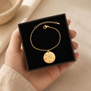 May include: A gold-colored bracelet with a circular pendant inside a black box. The pendant has engraved text that reads "Thank you for everything. You are the best. - Martin". The bracelet is displayed on a light-colored background.