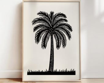 May include: Black and white palm tree art print in a wooden frame. The artwork features a detailed illustration of a palm tree with a textured trunk and feathery fronds. The print is set against a cream-colored background, with a strip of grass at the base.