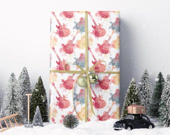 May include: A wrapped gift with a watercolor guitar pattern in red, blue, and yellow. The gift is tied with a gold ribbon and ornaments. Miniature Christmas trees and a toy car with a package on top are in a snowy setting.