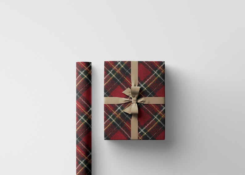 May include: A wrapped gift box and a roll of wrapping paper. Both are covered in a red, black, and gold plaid pattern. The gift box is tied with a tan ribbon and bow, creating a festive presentation.