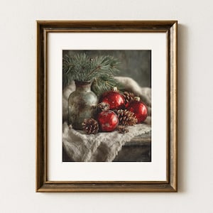 May include: Framed still life featuring a vintage glass vase with pine sprigs, red Christmas ornaments, and pine cones. The composition is set on a textured fabric, creating a rustic holiday scene. The frame is a warm, golden brown.