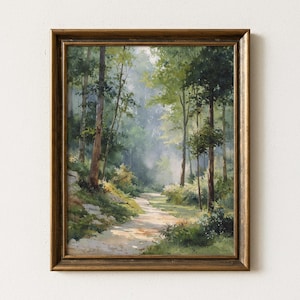 Puede incluir: Pintura de paisaje enmarcada que representa un sendero forestal bañado por el sol que serpentea a través de la exuberante vegetación. La obra de arte presenta árboles altos, un camino y luz suave y difusa, todo dentro de un marco dorado. La pintura evoca tranquilidad y belleza natural.