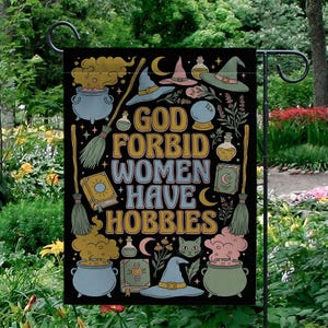 Könnte beinhalten: Schwarze Gartenflagge mit dem Text "GOD FORBID WOMEN HAVE HOBBIES" in Gold, Blau und Weiß. Die Flagge zeigt Illustrationen von Hexenhüten, Kesseln, Besen und Zaubertränken im Retro-Stil.
