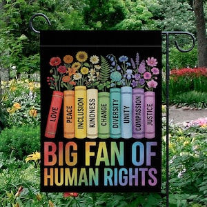 May include: A black garden flag with a colorful design. The flag features a row of books with titles like "Love" and "Justice," each topped with a different type of flower. The phrase "BIG FAN OF HUMAN RIGHTS" is printed in rainbow colors.
