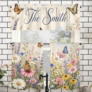 May include: Cream-colored kitchen curtains with a floral and butterfly design. The curtains feature a variety of colorful wildflowers, butterflies, and the text "The Smith" in navy blue script. The curtains are hung on a white tiled wall.