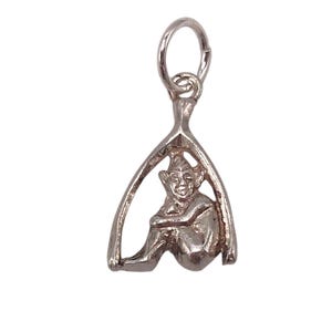 May include: Silver-toned charm pendant featuring a seated figure within a wishbone design. The figure is depicted with a smiling face and crossed arms. The pendant includes a small loop for attachment to a necklace or bracelet.