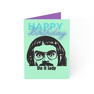 May include: A folded greeting card with a mint green front and a purple interior. The front features the words "HAPPY Birthday" in blue and a black and white illustration of a person with glasses and the text "Do it lady."