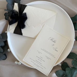 Black Ribbon Wedding Invitation – Cream Textured Card with Embossed Floral Design and Elegant Envelope