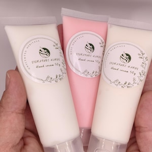 Può includere: Tre tubetti di crema per le mani bianchi, rosa e bianco sporco, tenuti in una mano. Ogni tubetto ha un tappo trasparente e un'etichetta con la scritta "SIGNATURE HANDS Hand cream 50g". Le etichette includono anche "UNSCENTED HERITAGE", "ROSE HERITAGE" e "LAVENDER HERITAGE".