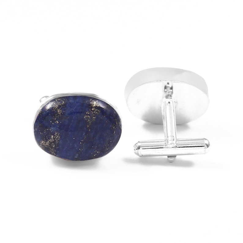 May include: A pair of cufflinks with oval lapis lazuli stones and silver-coloured metal settings. The dark blue stones have gold flecks. The cufflinks have a classic T-bar closure.
