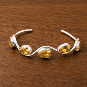 Può includere: Un bracciale a fascia in argento con un design a onda aperto alle estremità. Il bracciale è impreziosito da quattro pietre preziose di citrino giallo sfaccettate a forma di pera, ciascuna incastonata in una montatura liscia in argento.