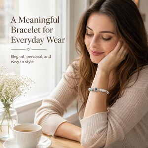 May include: A bracelet with white and light blue beads and a central dark blue charm. The bracelet is worn on a wrist. The image includes the text "A Meaningful Bracelet for Everyday Wear" and "Elegant, personal, and easy to style."