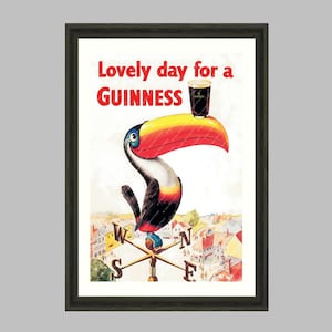 Puede incluir: Impresi&oacute;n art&iacute;stica enmarcada que presenta un tuc&aacute;n con un pico grande y colorido, sosteniendo una pinta de Guinness. La obra de arte incluye el texto "Lovely day for a Guinness" y un dise&ntilde;o de veleta. El marco es oscuro.