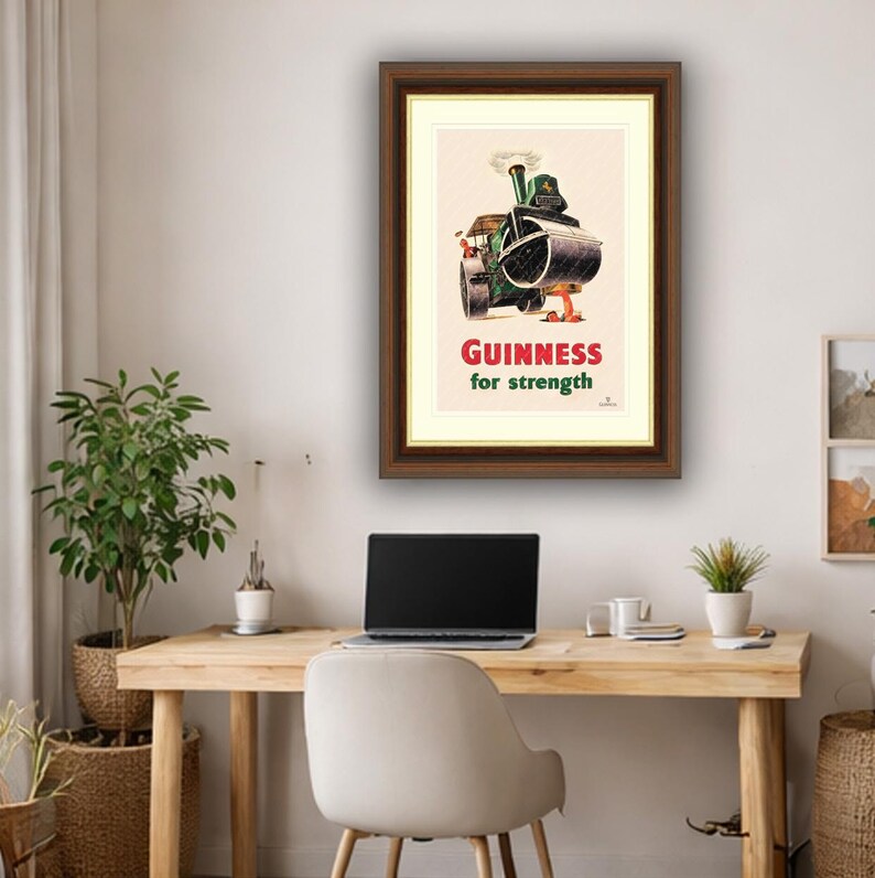 Puede incluir: Anuncio vintage enmarcado de Guinness. La obra de arte presenta un rodillo de vapor verde con el texto "Guinness for strength" en rojo y verde. La obra de arte est&aacute; en un marco marr&oacute;n.
