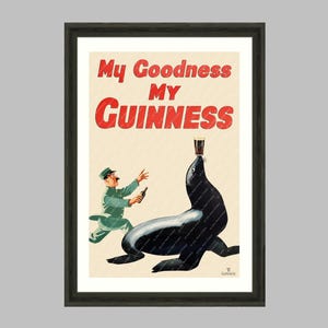 May include: Framed vintage Guinness advertisement print. The artwork features a seal balancing a pint of Guinness on its nose, with a man in a green uniform running towards it. The text "My Goodness My Guinness" is displayed in red.